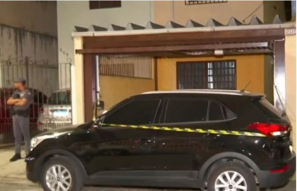 Reprodução/TV Globo foto colorida de policiais na frente da casa de adolescente que confessou ter matado a tiros os pais adotivos e a irmã em SP - Metrópoles
